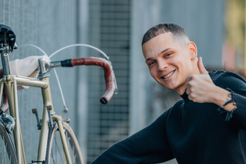 Wall Mural - young man on the street smiling with bicycle and okay sign