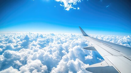 Wall Mural - Airplane wing and clear blue sky with fluffy cumulus clouds in a panoramic view, providing ample space for travel-related content.