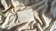 © ShStock - Blank paper card sheets with copy space on wrinkled bed blanket cloth with aesthetic warm sunlight shadows Flat lay top view