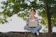 © ViDi Studio - Full body young woman wears shirt casual clothes work hold use laptop pc computer sits walk rest relax in spring sunshine green city park near sea outdoors on nature. Urban lifestyle leisure concept.