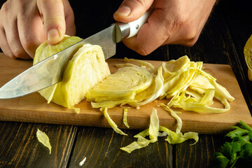 Wall Mural - Preparing to cook stewed cabbage. Knife in the cook hand for cutting cabbage on the kitchen board. Vegetable diet at home.