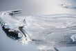 © Höyka Studio - Abstract piece of ice on a mirror background with reflection and refraction. Ice floe isolated. Play of light on the icy water. Textured bright ice surface. Effect of silver bright liquid metal