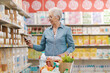 © StockPhotoPro - Senior woman checking supermarket products using her smartphone