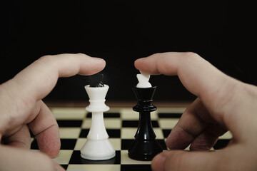 two hands placing two chess kings on a chessboard close-up, beginning of the game, betting on favori