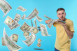 © New Africa - Man throwing money on light blue background. Dollar bills flying away from him