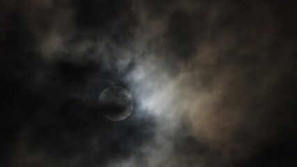 Wall Mural - The full moon shines down on the Earth at night, with occasional clouds obscuring the light.