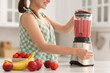 © New Africa - Woman making delicious smoothie with blender at white marble table in kitchen, closeup