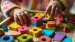 © Curioso.Photography - A child playing with colorful wooden geometric blocks on a table, showcasing early childhood learning and development.