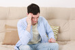 © New Africa - Man suffering from headache on sofa at home