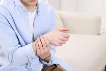 Canvas Print - Man suffering from pain in hand on sofa indoors, closeup. Space for text