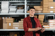 © New Africa - Smiling young man with clipboard near cardboard boxes in auto store