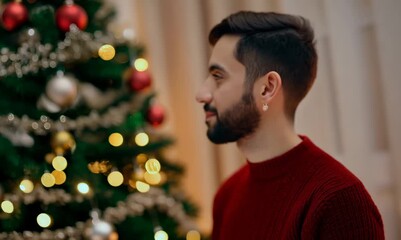 Sticker - Portrait of a handsome young man with a beard in a red sweater on the background of a Christmas tree