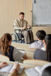 © Seventyfour - Vertical shot of adult male professor with disability presenting lecture on law in university classroom