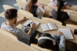 © Seventyfour - High angle shot of disinterested students sitting at desk with notebooks and mobile phones distracting from lecture at university class