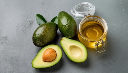 Wall Mural - Avocado oil in a glass jar with whole and half cut avocados beside it, isolated on white background. Natural beauty and health benefits of this versatile ingredient