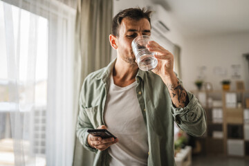 Portrait of adult men stand hold glass of water and mobile phone