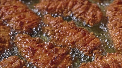 Wall Mural - crispy chicken meat pieces are fried in hot oil. the process of making a tasty snack, close-up of the food