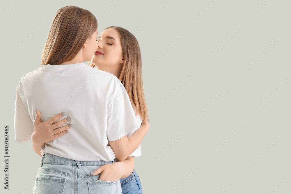 Young lesbian couple hugging on light background