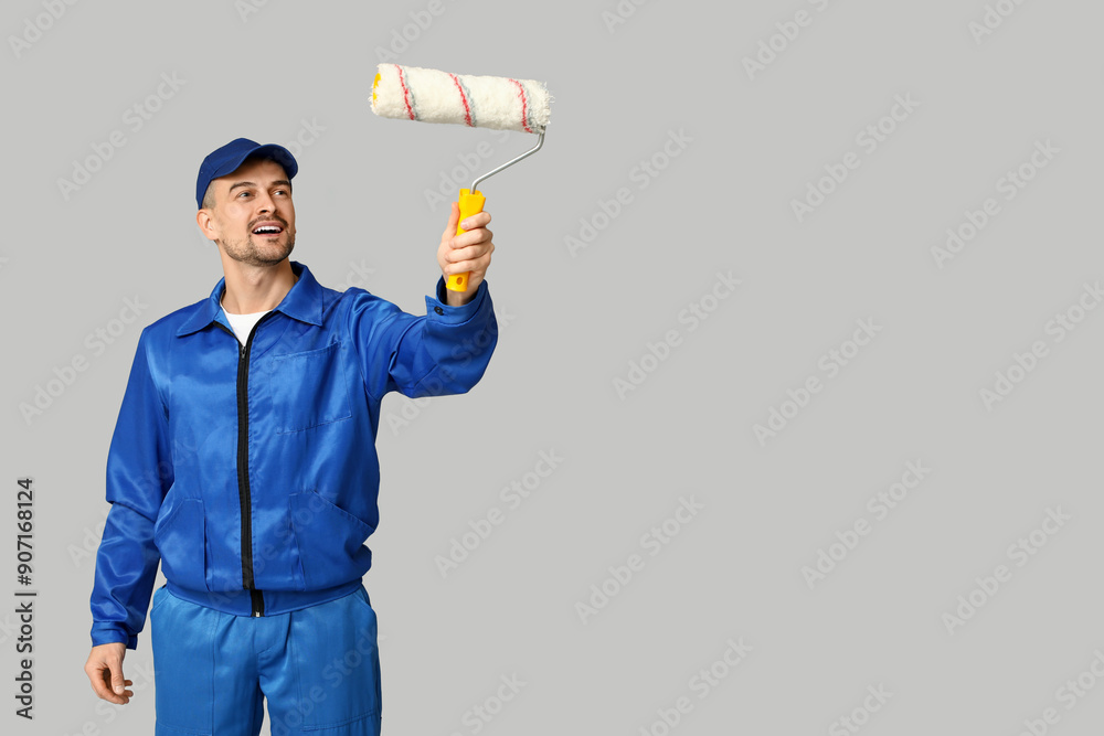 Portrait of male painter with paint roller on grey background