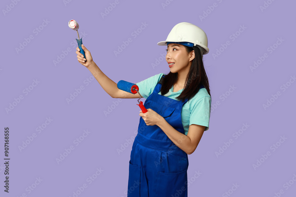 Female Asian painter with rollers on purple background