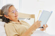 © ฺฺฺBoonterm - Elderly woman wearing glasses relaxing on bed reading novel : Relaxed asian retired senior sitting in his bedroom at home while reading book window enjoying living simple retirement life.