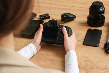 Canvas Print - Female photographer with professional equipment at wooden table, closeup