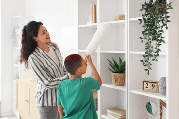 Canvas Print - Little African-American boy with his mother cleaning shelf at home