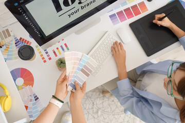 Poster - Female graphic designers working with color palettes at table in office, top view
