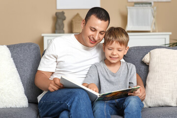 Canvas Print - Happy father with his little son reading book on sofa at home