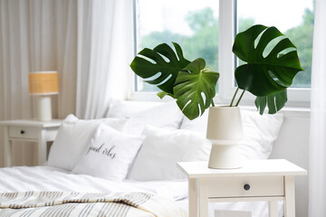 Poster - Vase with monstera leaves on bedside table in light bedroom