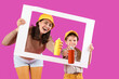 © Pixel-Shot - Little girl and her mother holding spray paint cans and paper frame on purple background