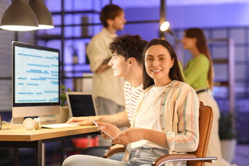 Female programmer with tablet computer working in office at night