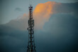 © Emvats - A communication tower stands tall against a backdrop of clouds, with a hint of sunlight illuminating the sky. The metal structure is prominent in the serene setting, providing ample copy space.