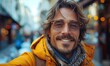© Igal - A handsome young man is taking a selfie on a city street, smiling happily and walking outdoors.