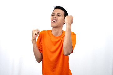 Portrait of a young Asian man wearing an orange t-shirt with a happy expression, surprised to get good news. Isolated on white background.