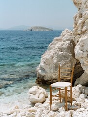 Wall Mural - A chair on a white rock on the beach, Greece, has a clear blue sky and the Mediterranean Sea