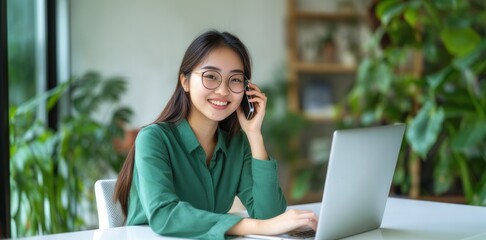 Wall Mural - Asian woman sitting at a white desk using a laptop and waving her hand.