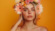 © Anas - A woman with light hair, wearing an orange shirt and a vibrant flower crown, standing in front of an orange backdrop.