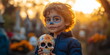 © Vasiliy - A young boy with skull makeup holds a decorative sugar skull in a cemetery. Traditions and cultural significance of Day of the Dead
