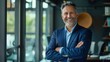 © Boraryn - Happy middle aged business man ceo standing in office arms crossed. Smiling mature confident professional executive manager, proud lawyer, businessman leader wearing blue suit