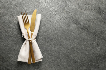 Wall Mural - Stylish golden cutlery and napkin on grey table, top view. Space for text