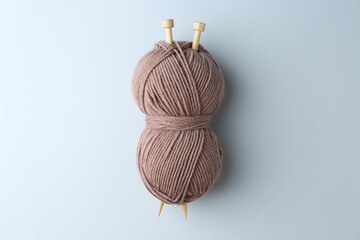 Wall Mural - Brown yarn with knitting needles on light grey background, top view