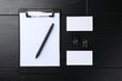 © New Africa - Blank business cards, clipboard with sheet, pen and binder clips on black wooden table, flat lay. Mockup for design