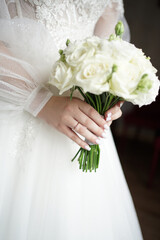 Canvas Print - The bride in a wedding dress with a wedding ring on her finger is holding a bouquet of flowers. Preparation for the wedding.