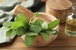 © New Africa - Green sage leaves and pestle in mortar on wooden table, closeup