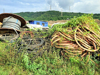 A collection of used cables overgrown with grass which are usually used in the power generation industry