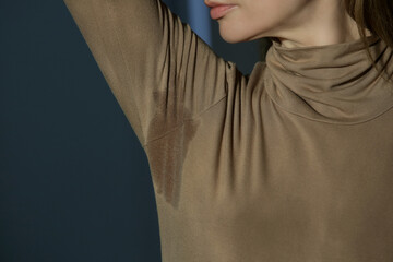 Wall Mural - Close up image of woman in beige cotton turtleneck with sweat patch under armpit	