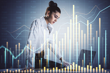 Canvas Print - Businesswoman analyzing stock market data on laptop with charts and graphs in background.