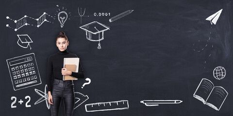 Aufkleber - Female student holding books in front of a chalkboard with various educational icons drawn in chalk..