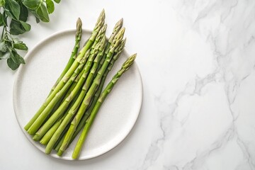 Fresh green asparagus spears on white plate with marble background